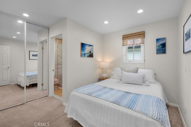 bedroom with light colored carpet, a closet, and ensuite bathroom