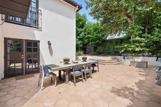 view of patio / terrace featuring french doors, an outdoor fire pit, and a storage unit