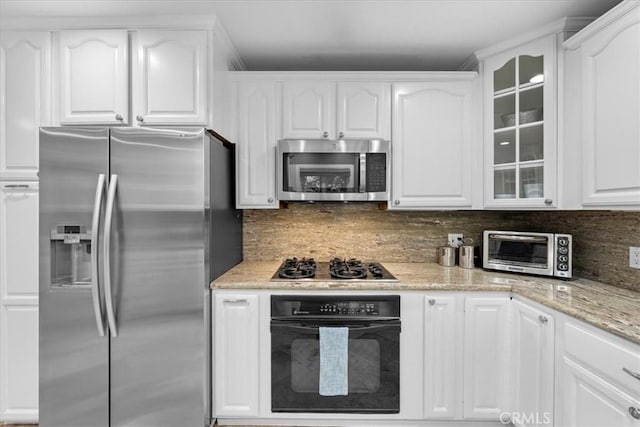 kitchen with tasteful backsplash, light stone countertops, stainless steel appliances, and white cabinets