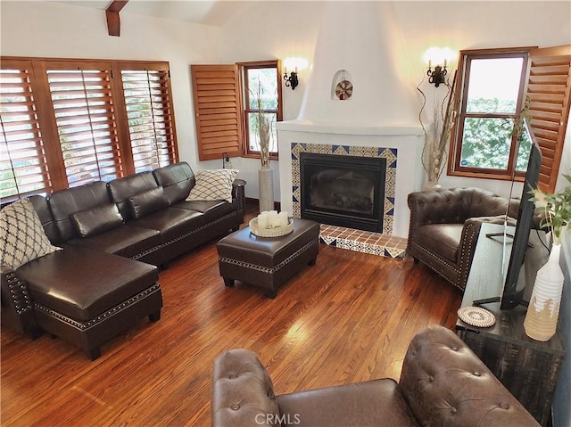 living room featuring a tile fireplace, hardwood / wood-style floors, a wealth of natural light, and beam ceiling