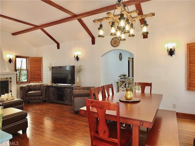 dining space with wood-type flooring, high vaulted ceiling, and a chandelier