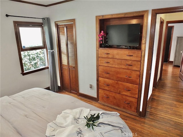 bedroom featuring dark hardwood / wood-style floors, ornamental molding, and a closet