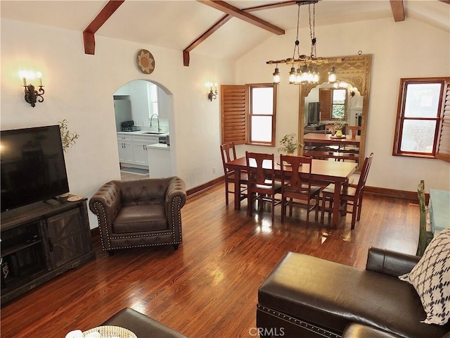 living room featuring lofted ceiling with beams, dark hardwood / wood-style floors, an inviting chandelier, and sink