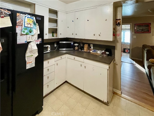 kitchen featuring white cabinetry, black fridge, and light hardwood / wood-style floors