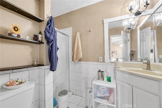 bathroom featuring walk in shower, vanity, an inviting chandelier, tile walls, and toilet