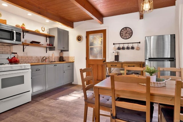 kitchen featuring gray cabinetry, pendant lighting, tasteful backsplash, light hardwood / wood-style floors, and stainless steel appliances