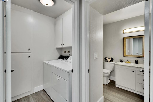 washroom featuring cabinets, light wood-type flooring, and separate washer and dryer