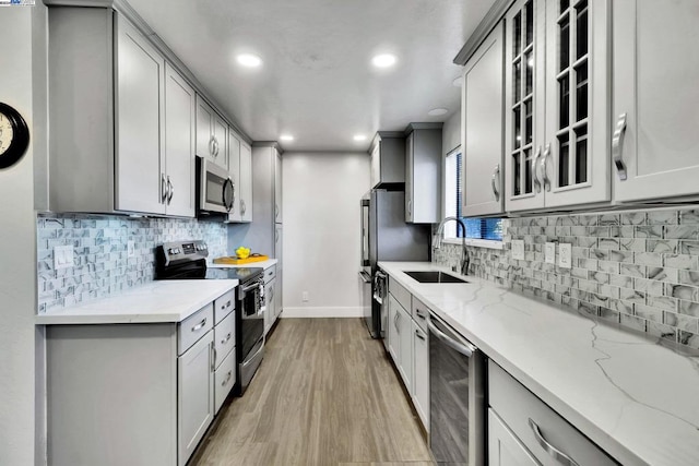 kitchen with light stone counters, sink, light hardwood / wood-style floors, and appliances with stainless steel finishes