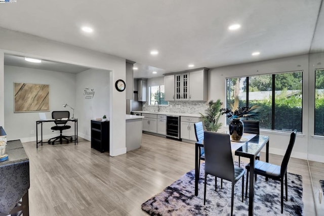 dining room with light hardwood / wood-style floors, beverage cooler, and sink