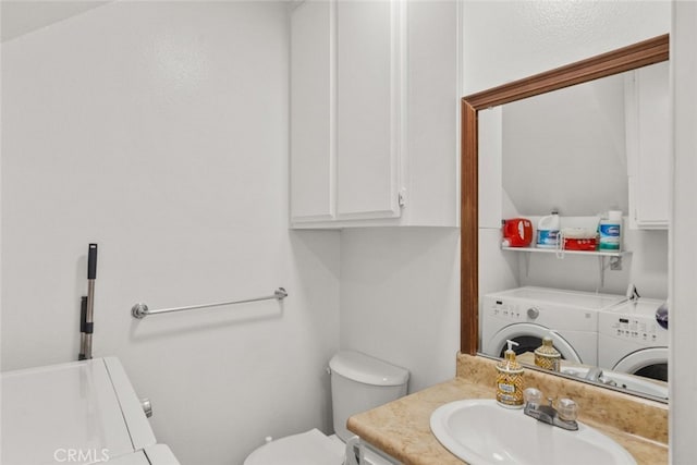 bathroom with washing machine and clothes dryer, vanity, and toilet