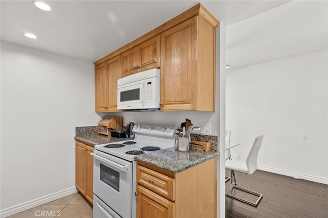 kitchen featuring white appliances, dark stone counters, and light hardwood / wood-style flooring