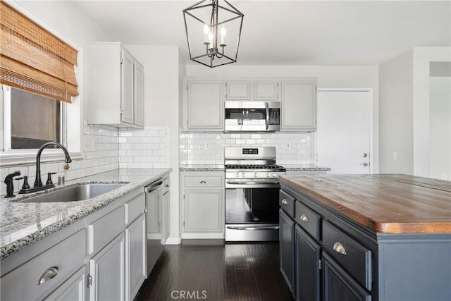 kitchen featuring backsplash, sink, hanging light fixtures, dark hardwood / wood-style flooring, and stainless steel appliances