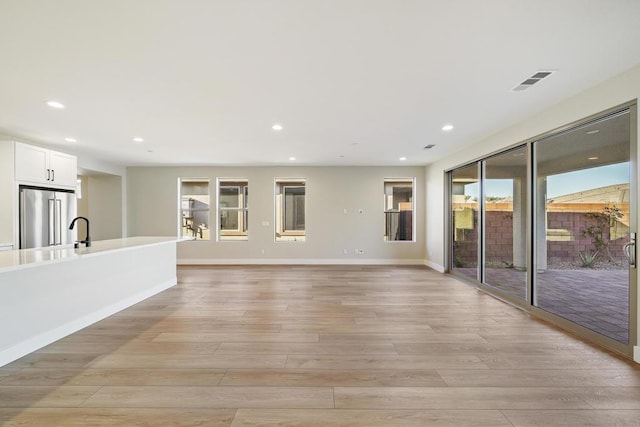 unfurnished living room with sink and light wood-type flooring