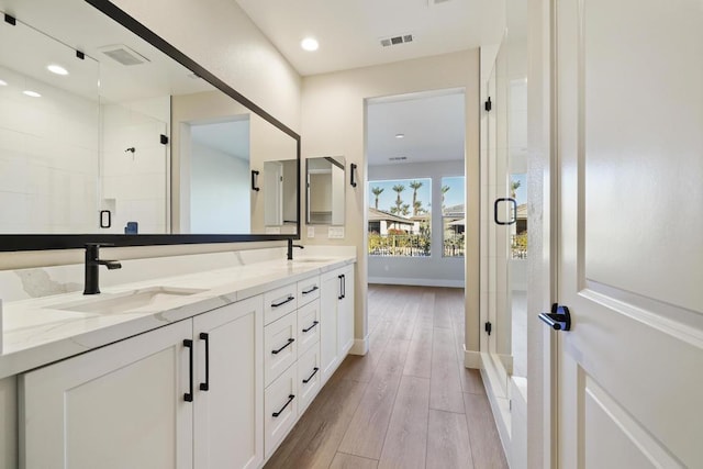 bathroom with vanity, a shower with shower door, and wood-type flooring