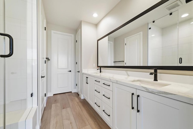 bathroom with hardwood / wood-style floors, vanity, and a shower with door