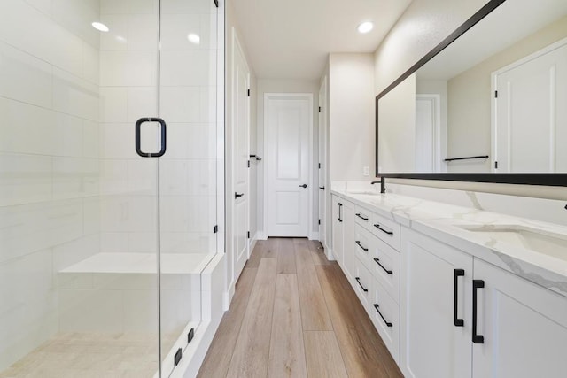 bathroom with wood-type flooring, vanity, and a shower with door