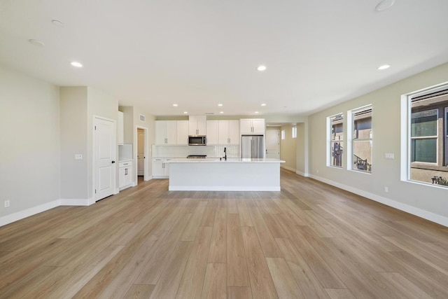 unfurnished living room featuring sink and light hardwood / wood-style flooring