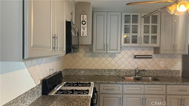 kitchen featuring gas range oven, decorative backsplash, and sink