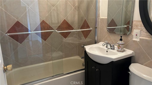 full bathroom with tasteful backsplash, vanity, shower / bath combination with glass door, tile walls, and toilet