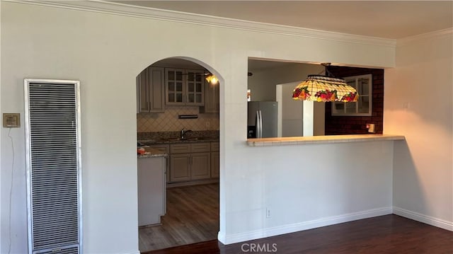 kitchen with stainless steel fridge, tasteful backsplash, crown molding, sink, and dark hardwood / wood-style floors