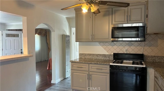 kitchen featuring gas range oven, dark hardwood / wood-style flooring, light stone countertops, and backsplash