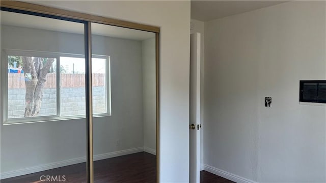 unfurnished bedroom with a closet and dark wood-type flooring