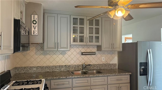 kitchen with backsplash, stainless steel appliances, ceiling fan, sink, and stone counters