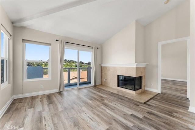 unfurnished living room featuring hardwood / wood-style flooring, a multi sided fireplace, a wealth of natural light, and vaulted ceiling