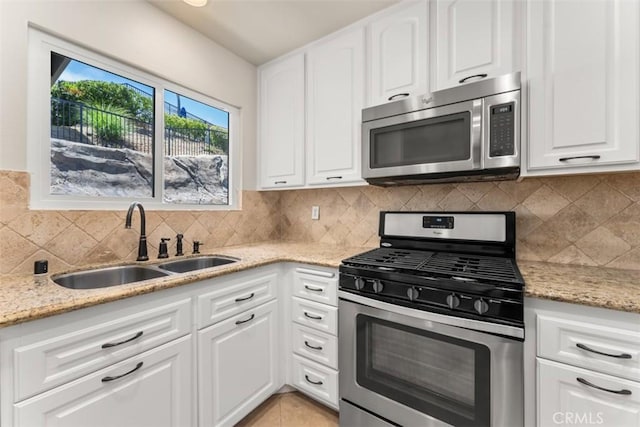 kitchen with white cabinets, light stone counters, sink, and appliances with stainless steel finishes