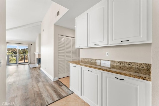 kitchen featuring light hardwood / wood-style floors, white cabinetry, and dark stone countertops