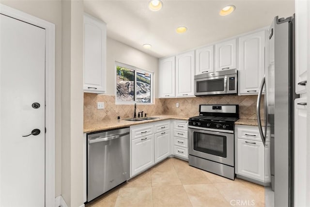 kitchen with white cabinetry, sink, light stone counters, and appliances with stainless steel finishes