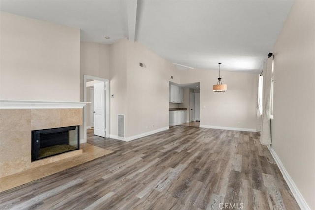 unfurnished living room featuring a fireplace, lofted ceiling with beams, and hardwood / wood-style flooring