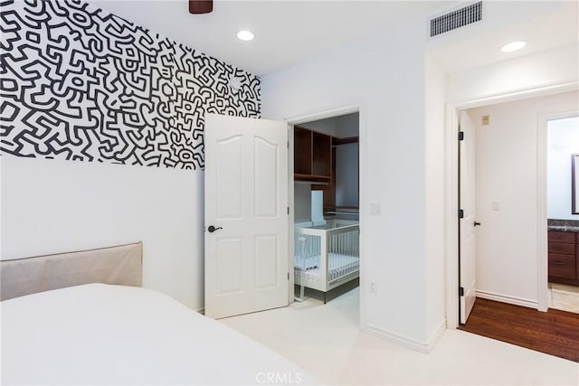 bedroom with ensuite bathroom and hardwood / wood-style floors