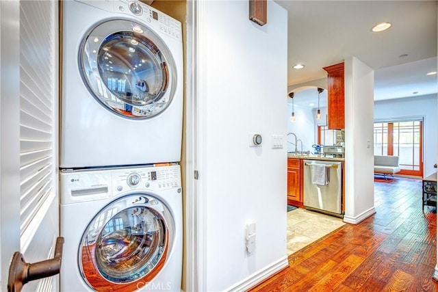 washroom with stacked washer / dryer and light hardwood / wood-style flooring