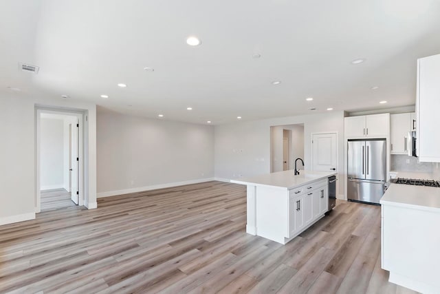 kitchen featuring sink, light hardwood / wood-style floors, a kitchen island with sink, white cabinets, and appliances with stainless steel finishes