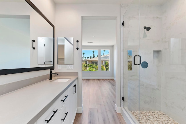 bathroom with hardwood / wood-style floors, vanity, and a shower with shower door