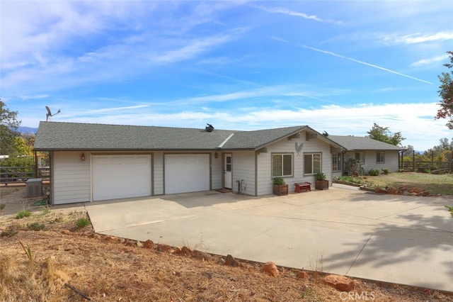 ranch-style home with a garage and central AC unit