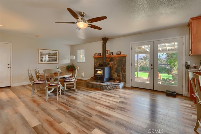 dining area with french doors, light hardwood / wood-style flooring, a wood stove, and ceiling fan