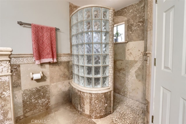 bathroom with a tile shower and tile walls