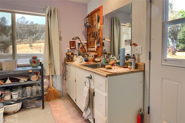 bar featuring a wealth of natural light, sink, and white cabinets