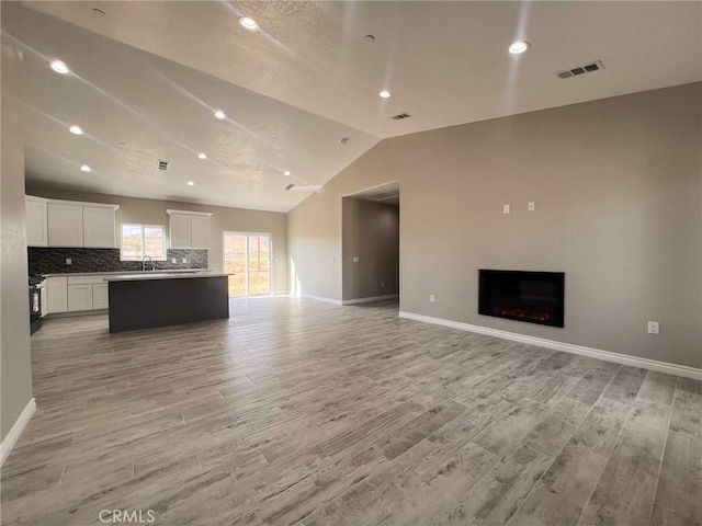 unfurnished living room with lofted ceiling and light wood-type flooring