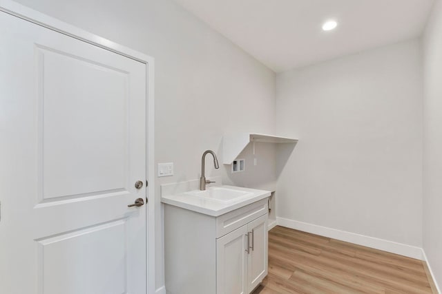 clothes washing area with light wood-type flooring and sink