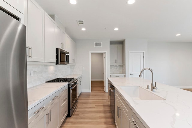 kitchen with white cabinetry, sink, stainless steel appliances, and light stone counters