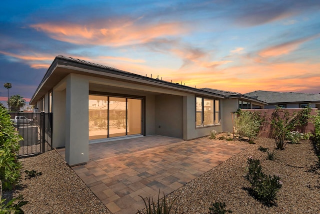 back house at dusk featuring a patio