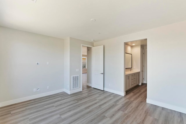 unfurnished bedroom with light wood-type flooring and ensuite bath