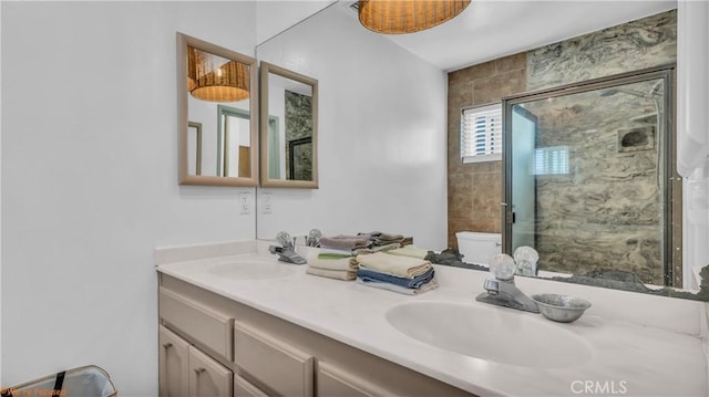 bathroom with a stall shower, a sink, toilet, and double vanity