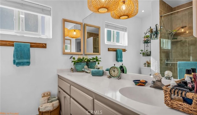 full bath with a sink, double vanity, a tile shower, and toilet