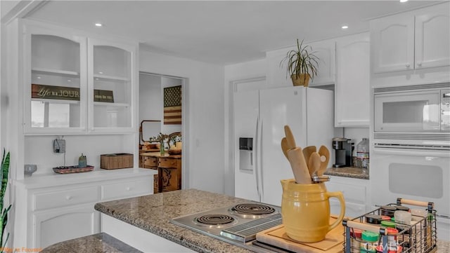 kitchen featuring glass insert cabinets, dark stone counters, white appliances, and white cabinetry