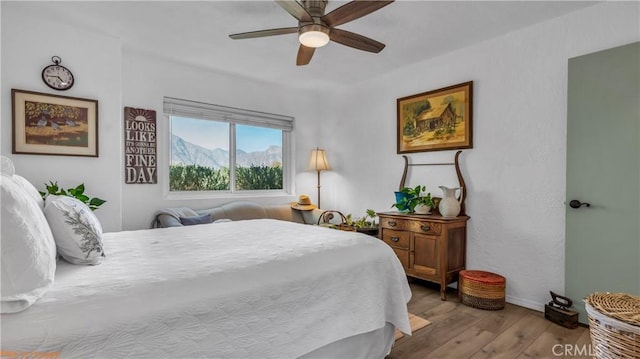 bedroom with light wood-type flooring, a mountain view, and a ceiling fan