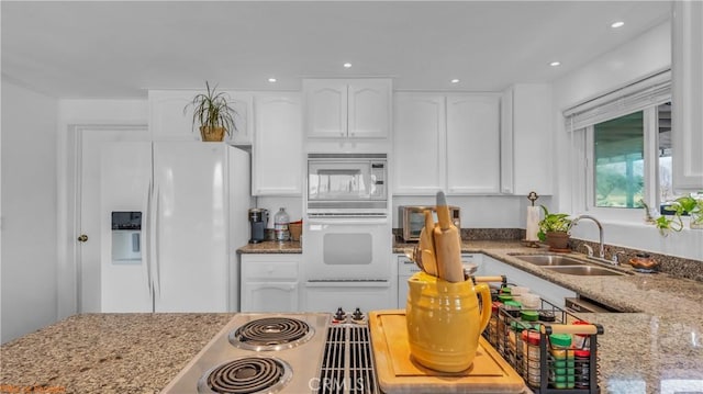 kitchen with recessed lighting, white appliances, a sink, white cabinets, and light stone countertops